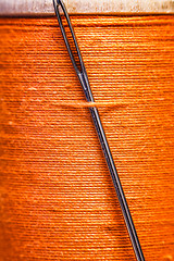 Image showing Spool of yellow thread with a needle stuck in it.