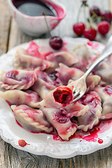 Image showing Plate with cherry dumplings and red sauce.