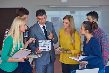 Image showing group of students working with teacher on  house model