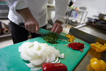 Image showing chef in hotel kitchen  slice  vegetables with knife