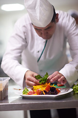 Image showing chef in hotel kitchen preparing and decorating food