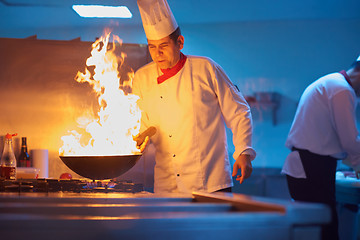 Image showing chef in hotel kitchen prepare food with fire