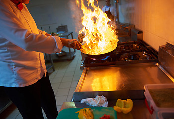 Image showing chef in hotel kitchen prepare food with fire