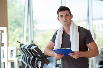 Image showing trainer with clipboard standing in a bright gym