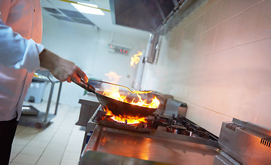 Image showing chef in hotel kitchen prepare food with fire