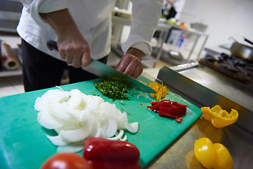 Image showing chef in hotel kitchen  slice  vegetables with knife