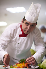 Image showing chef in hotel kitchen preparing and decorating food