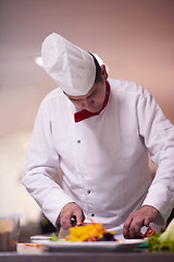 Image showing chef in hotel kitchen preparing and decorating food