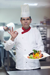 Image showing chef in hotel kitchen preparing and decorating food