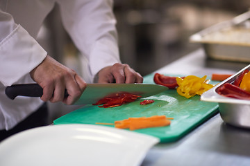 Image showing chef in hotel kitchen  slice  vegetables with knife