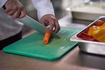 Image showing chef in hotel kitchen  slice  vegetables with knife