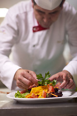 Image showing chef in hotel kitchen preparing and decorating food