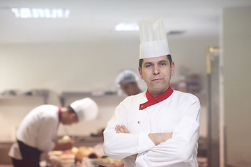 Image showing chef in hotel kitchen preparing and decorating food