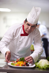 Image showing chef in hotel kitchen preparing and decorating food