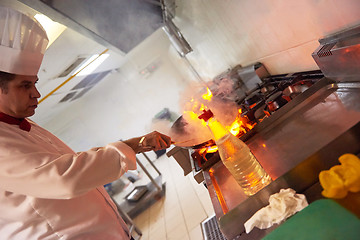 Image showing chef in hotel kitchen prepare food with fire