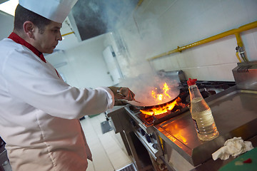 Image showing chef in hotel kitchen prepare food with fire