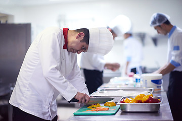 Image showing chef in hotel kitchen  slice  vegetables with knife