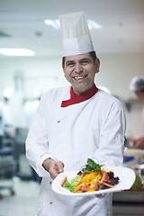 Image showing chef in hotel kitchen preparing and decorating food