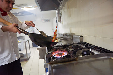 Image showing chef in hotel kitchen prepare food with fire