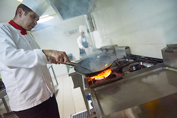 Image showing chef in hotel kitchen prepare food with fire