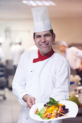 Image showing chef in hotel kitchen preparing and decorating food