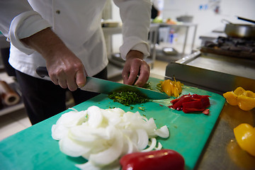 Image showing chef in hotel kitchen  slice  vegetables with knife