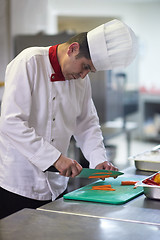 Image showing chef in hotel kitchen  slice  vegetables with knife