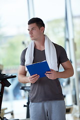 Image showing trainer with clipboard standing in a bright gym