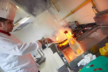 Image showing chef in hotel kitchen prepare food with fire