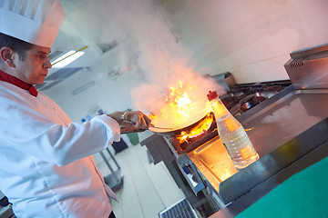 Image showing chef in hotel kitchen prepare food with fire