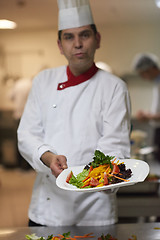 Image showing chef in hotel kitchen preparing and decorating food