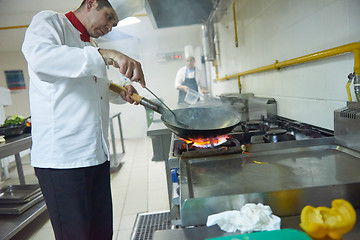 Image showing chef in hotel kitchen prepare food with fire