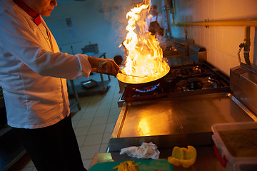 Image showing chef in hotel kitchen prepare food with fire