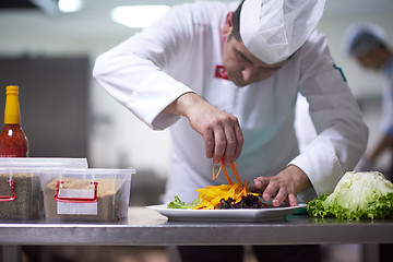 Image showing chef in hotel kitchen preparing and decorating food