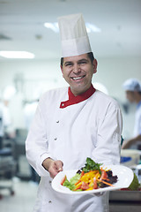 Image showing chef in hotel kitchen preparing and decorating food