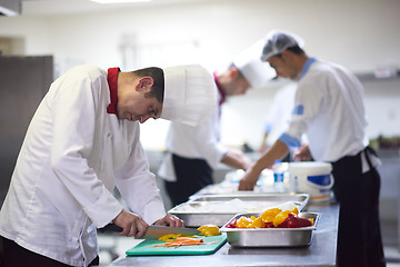 Image showing chef in hotel kitchen  slice  vegetables with knife