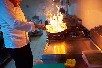 Image showing chef in hotel kitchen prepare food with fire