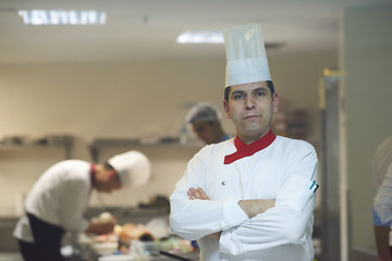 Image showing chef in hotel kitchen preparing and decorating food