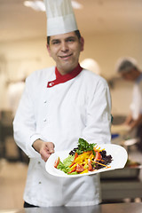 Image showing chef in hotel kitchen preparing and decorating food