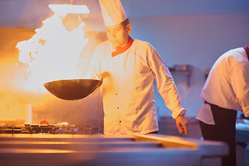 Image showing chef in hotel kitchen prepare food with fire