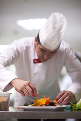 Image showing chef in hotel kitchen preparing and decorating food