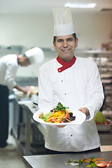 Image showing chef in hotel kitchen preparing and decorating food