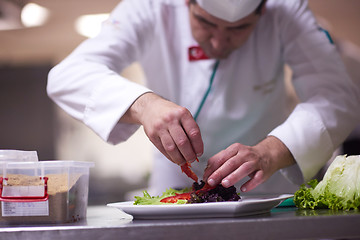 Image showing chef in hotel kitchen preparing and decorating food