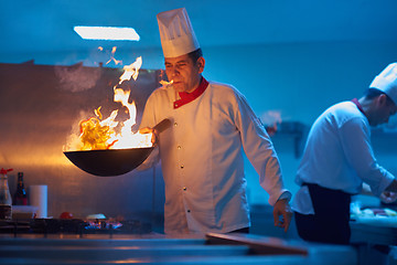 Image showing chef in hotel kitchen prepare food with fire