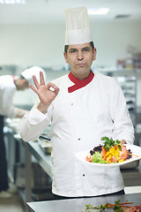 Image showing chef in hotel kitchen preparing and decorating food