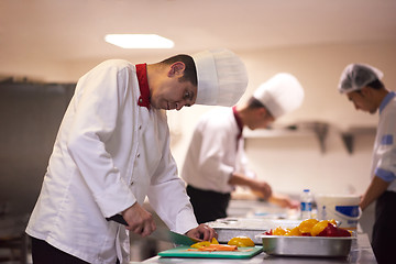 Image showing chef in hotel kitchen preparing and decorating food