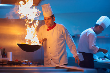 Image showing chef in hotel kitchen prepare food with fire