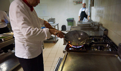 Image showing chef in hotel kitchen prepare food with fire