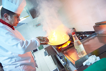 Image showing chef in hotel kitchen prepare food with fire