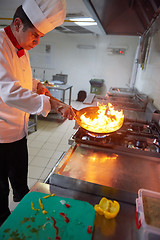 Image showing chef in hotel kitchen prepare food with fire